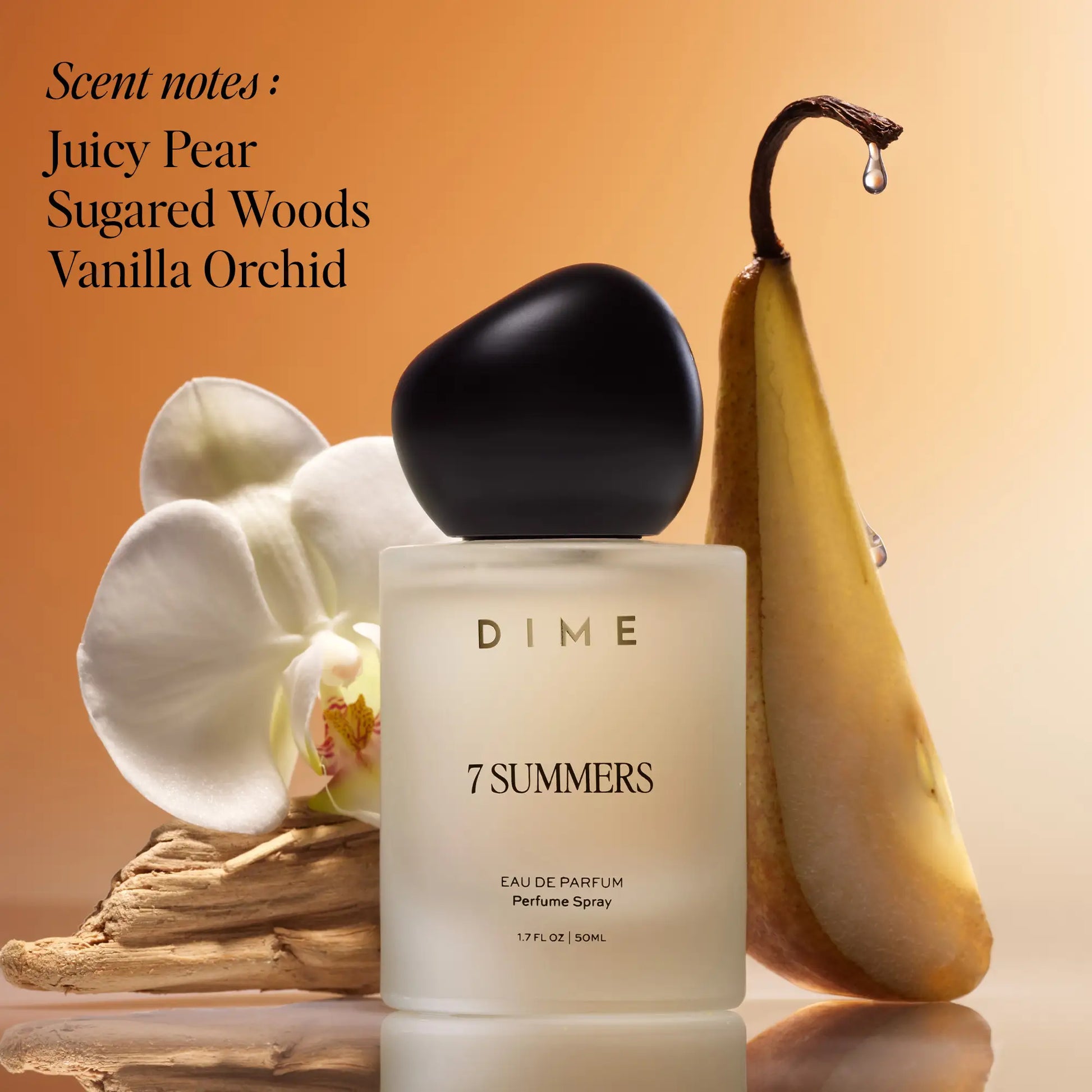 White cylindrical perfume bottle with black cap, 50ml, surrounded by white orchid flowers, driftwood, and a pear-shaped decor