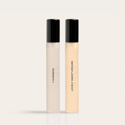 Two fragrance rollerballs with black caps labeled "7 Summers" and "Lovely Sweet Dreams" in cream and pale yellow liquid.
