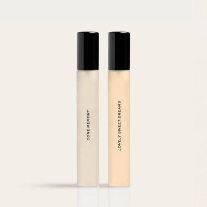 Two cylindrical fragrance bottles with black caps labeled "Core Memory" and "Lovely Sweet Dreams" in cream and pale peach liq