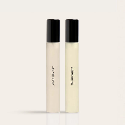 Two tall cylindrical fragrance bottles with black caps labeled "Core Memory" and "Malibu Night" containing clear liquid.
