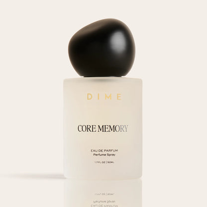 Cream-colored perfume bottle labeled "Core Memory" with black spherical cap, 1.7 fl oz size.