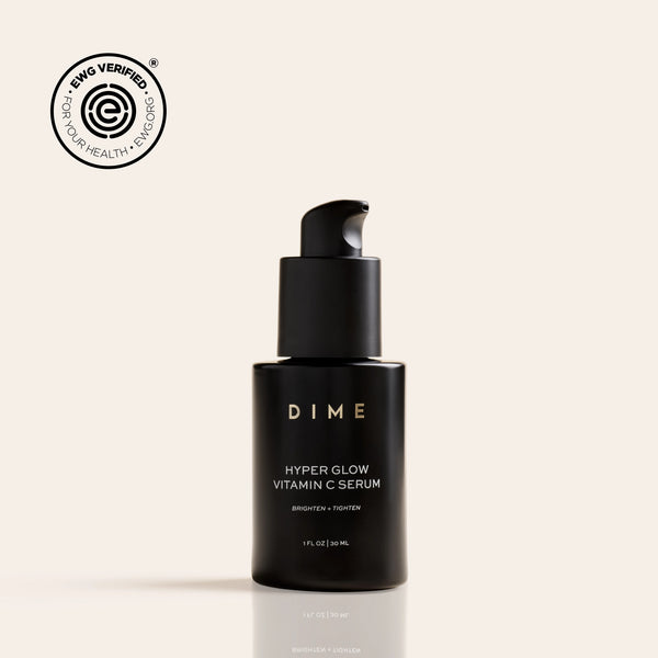 Black pump bottle labeled "Hyper Glow Vitamin C Serum" by DIME with EWG Verified seal on beige background.