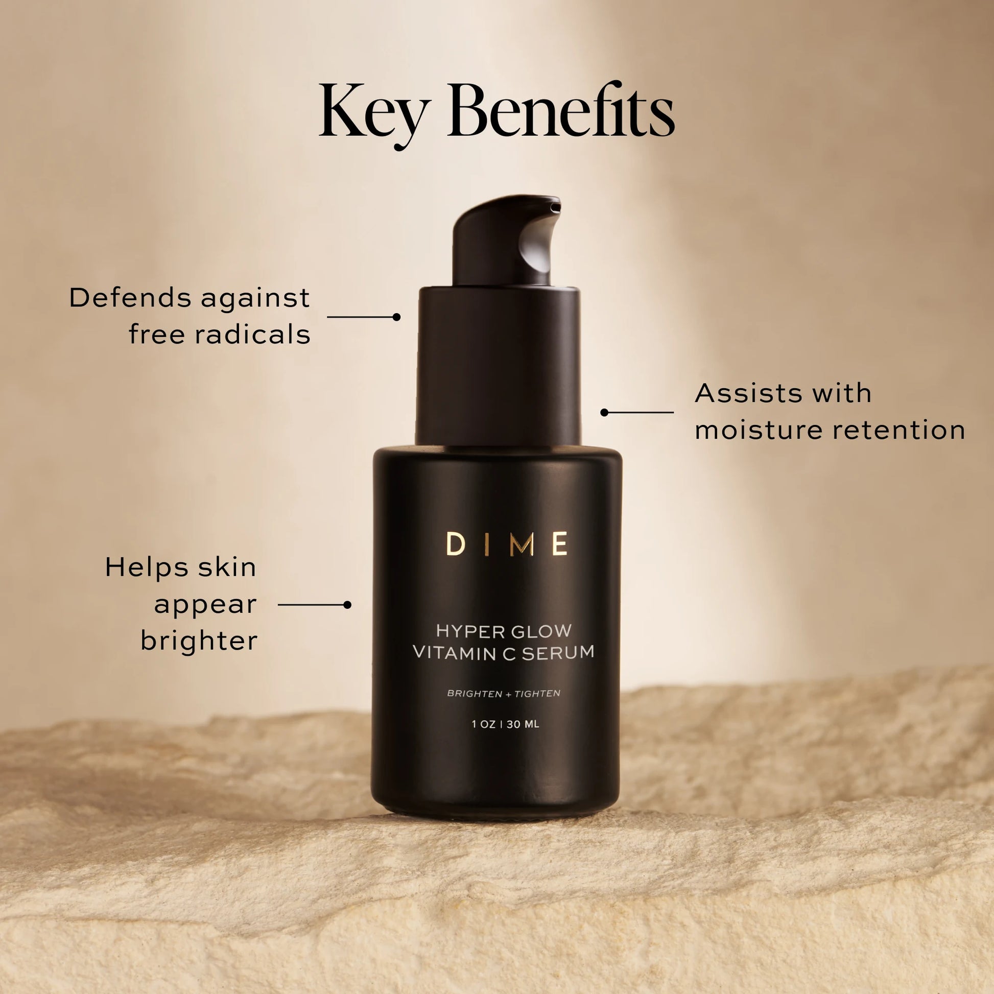 Black pump bottle of Hyper Glow Vitamin C Serum with labeled benefits displayed on sandy background.