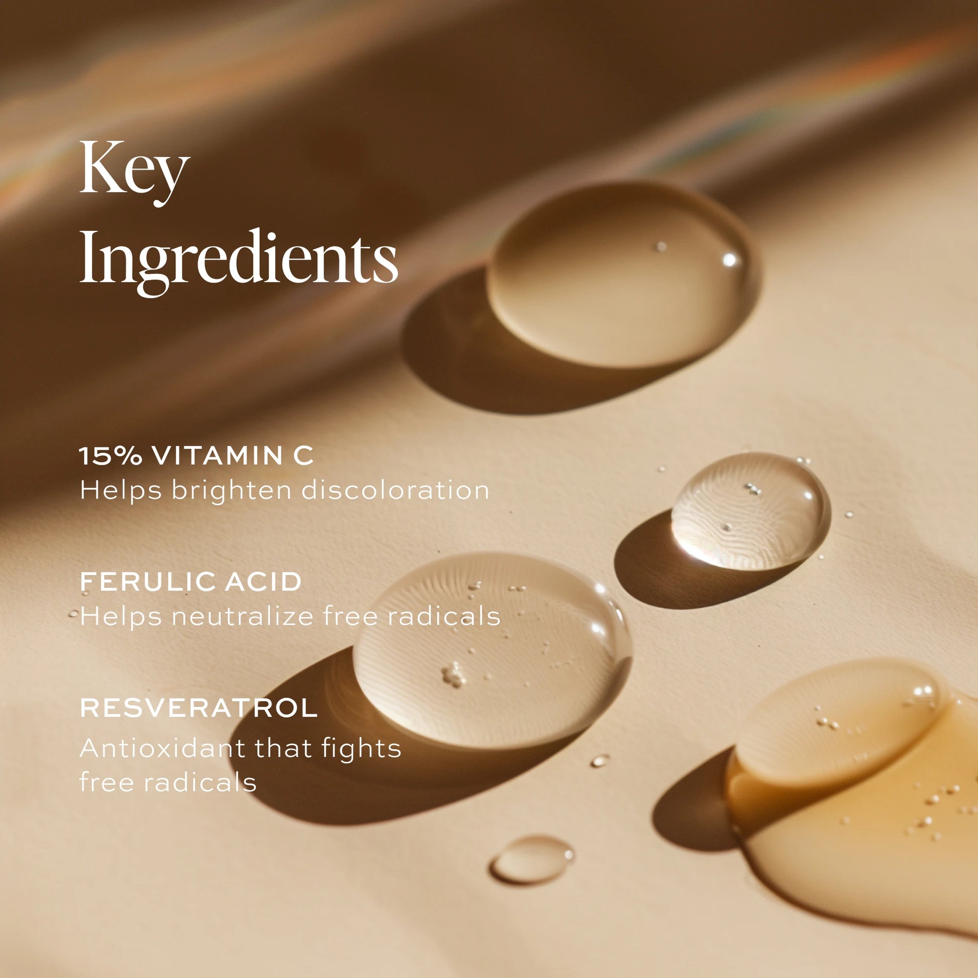 Beige liquid serum droplets on tan surface with ingredient text overlay listing vitamin C, ferulic acid, and resveratrol.