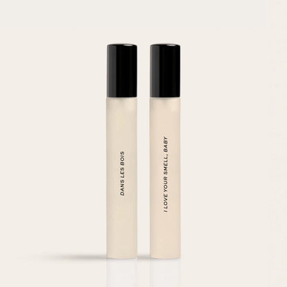 Two cream-colored roll-on fragrance bottles with black caps labeled "Dawns Les Bois" and "I Love Your Smell Baby".