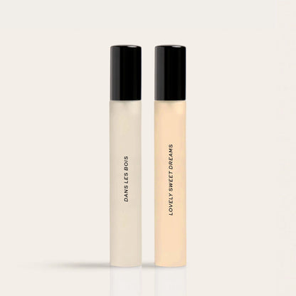 Two cylindrical fragrance bottles with black caps labeled "Daisies Body" and "Lovely Sweet Dreams" in cream and pale yellow l