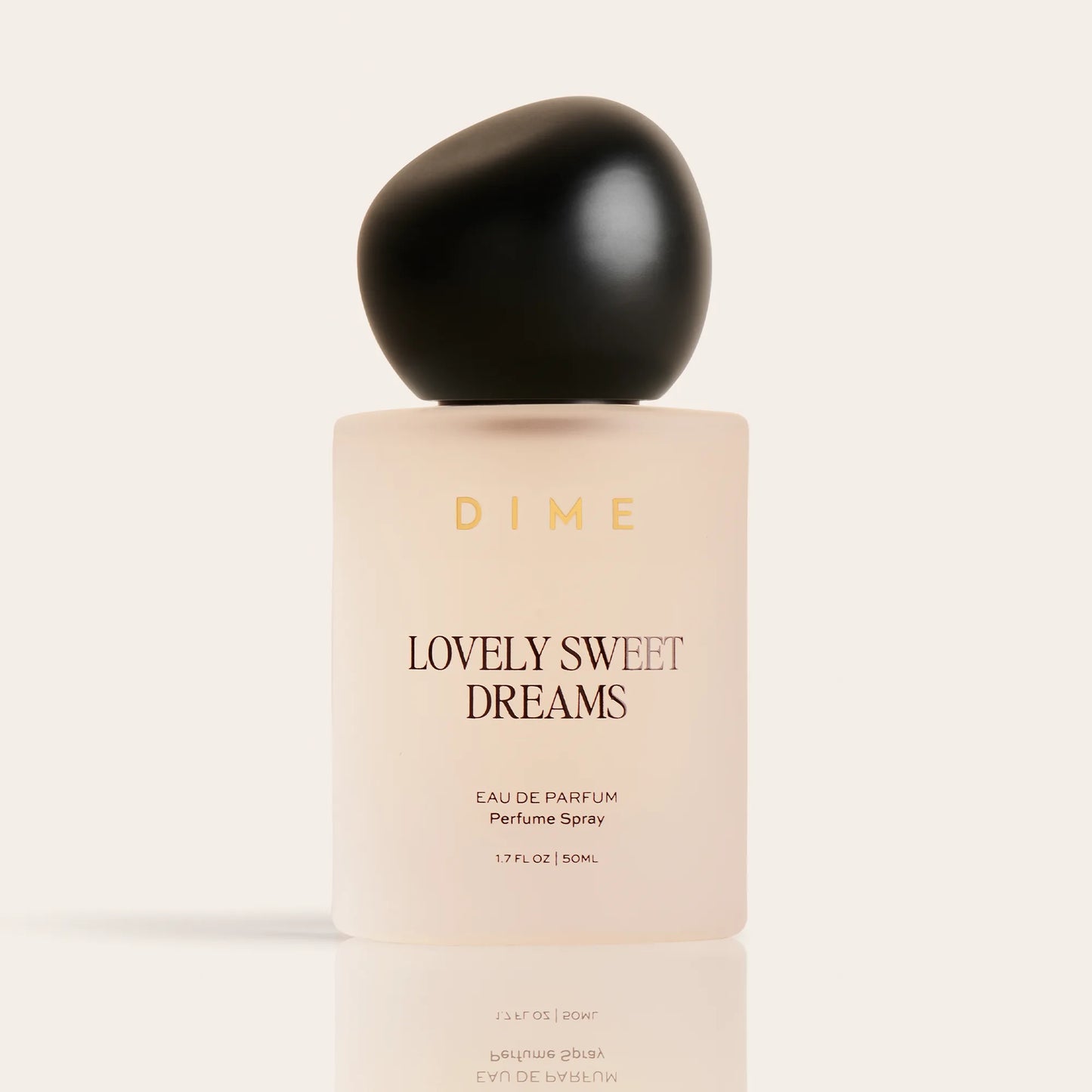 Cream-colored perfume bottle labeled "Lovely Sweet Dreams" with black spherical cap, 1.7 fl oz size.
