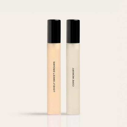 Two cylindrical fragrance bottles with black caps: one containing peachy liquid labeled "Lovely Sweet Dreams" and one contain