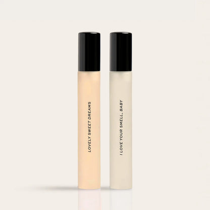 Two slim cylindrical fragrance bottles with black caps, one containing pale yellow liquid labeled "Lovely Sweet Dreams" and o
