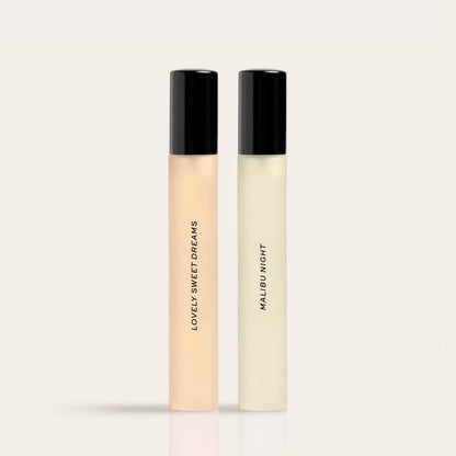 Two roll-on fragrance bottles with black caps, one containing peachy liquid labeled "Lovely Sweet Dreams" and one with pale y