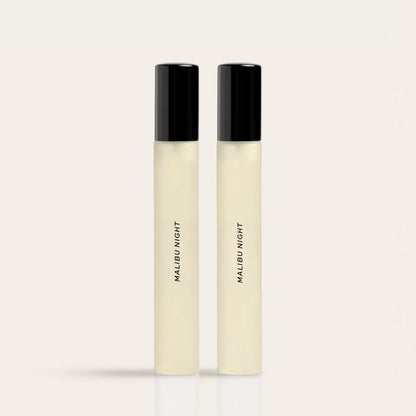 Two cylindrical fragrance bottles with black caps and cream-colored liquid labeled "Malibu Night."