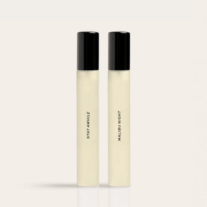 Two cylindrical fragrance bottles with black caps containing pale liquid labeled "Staywwhile" and "Malbumight."
