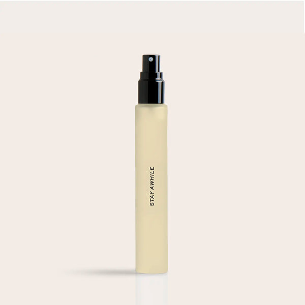 Pale yellow cylindrical spray bottle with black atomizer top and "STAY AWHILE" text on label.