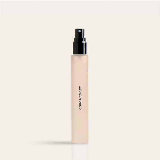Cream-colored travel perfume spray bottle with black pump top and "Core Memory" text on label.