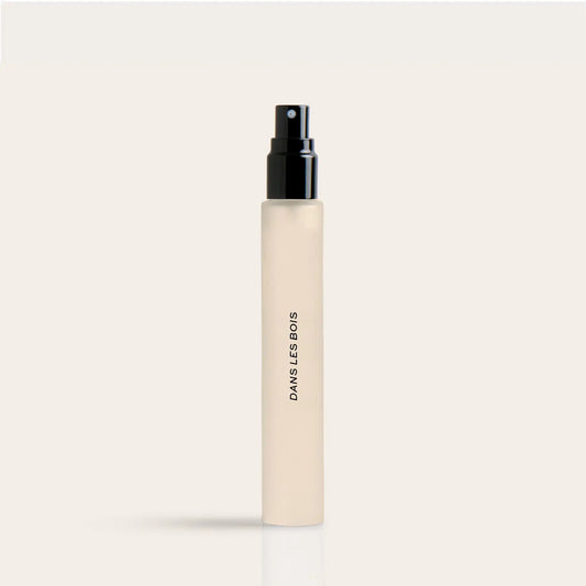 Cylindrical cream-colored spray bottle with black pump top and "DANS LES BOIS" text on side.