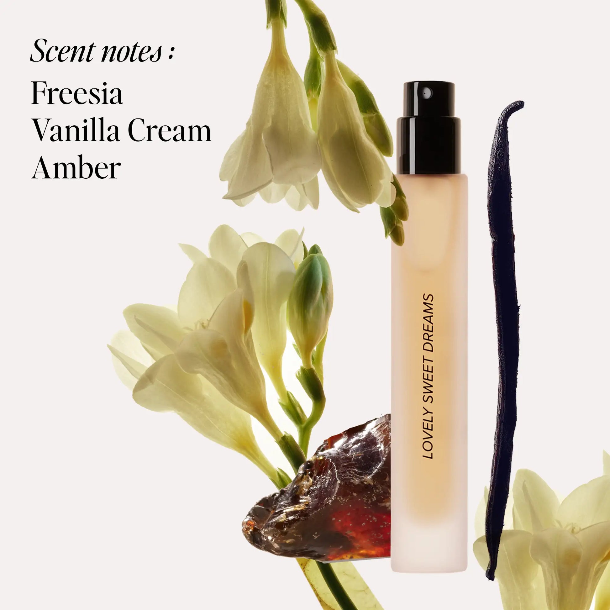 Pale perfume spray bottle with black atomizer surrounded by freesia flowers and vanilla bean.