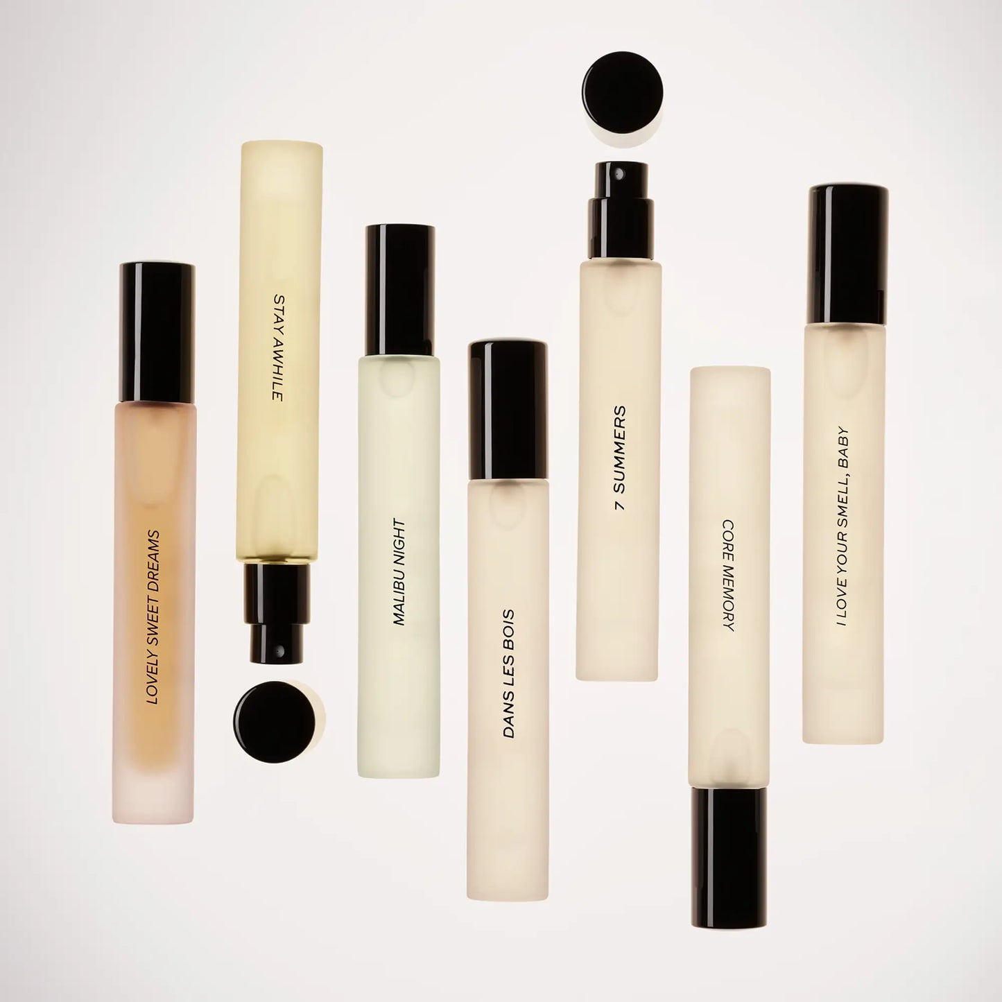 Perfume travel spray with cream-colored rectangular bottle, black cap, and spray nozzle containing pale liquid.