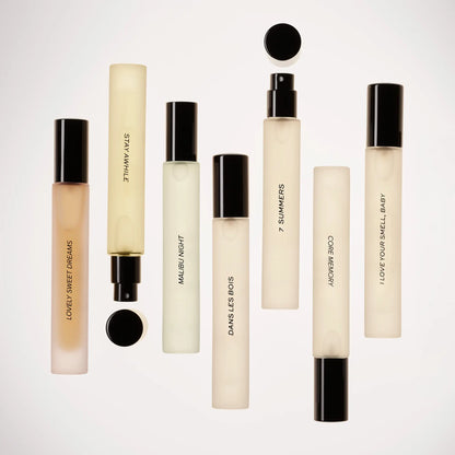 Perfume travel spray with cream-colored rectangular bottle, black cap, and spray nozzle containing pale liquid.